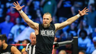 Bryan Danielson in the ring, with his arms in the air, in a black 'Be Real' t-shirt, ahead of AEW All Out 2024.