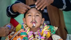 People prepare a child to be presented as the Andean god of abundance during the Alasitas fair in La Paz, Bolivia