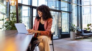 Woman working on laptop in front of office building