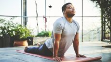 A man performs cobra pose on a yoga mat
