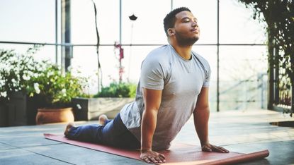 A man performs cobra pose on a yoga mat