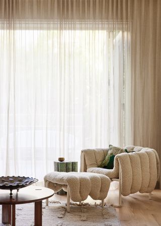 A detailed boucle accent chair and footstall in a light neutral living room