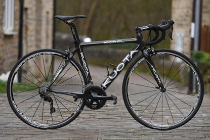 The Kuota Kebel is pictured side on, handle bars to the right on a cobbled street 