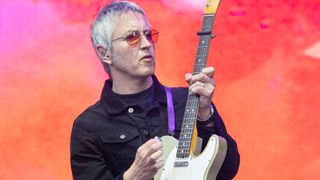 Gem Archer plays a Telecaster against a red-pink backdrop