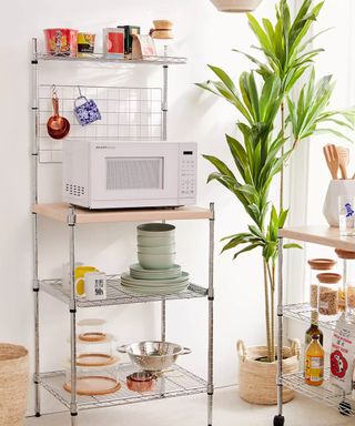 Kitchen with microwave on freestanding metal and wood shelving and plant