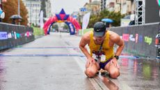 a tired runner kneels on the ground after a race