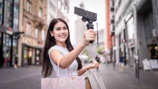 Mixed race woman traveler use camera record vlog while travel in city. Attractive female tourist feel happy and relax while walking on street, enjoy taking a photo during vacation trip in Frankfurt.