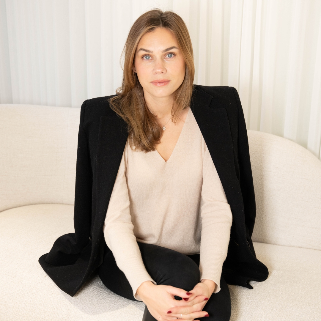 Image of Johanna Eriksson Hamrén, CEO of CAIA, with long blonde hair, wearing a cream V-neck jumper and black blazer