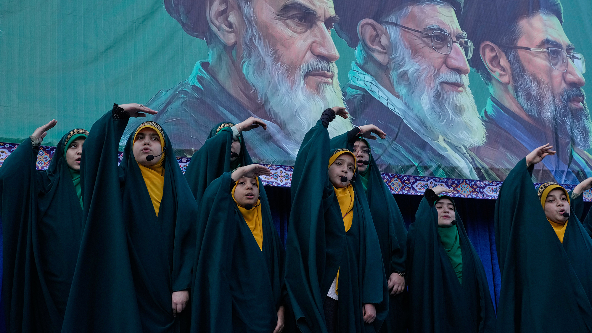 A group of girls sing as they mimic the flight of missiles with their hands during a rally celebrating the birthday of Imam Reza, in Tehran, Iran