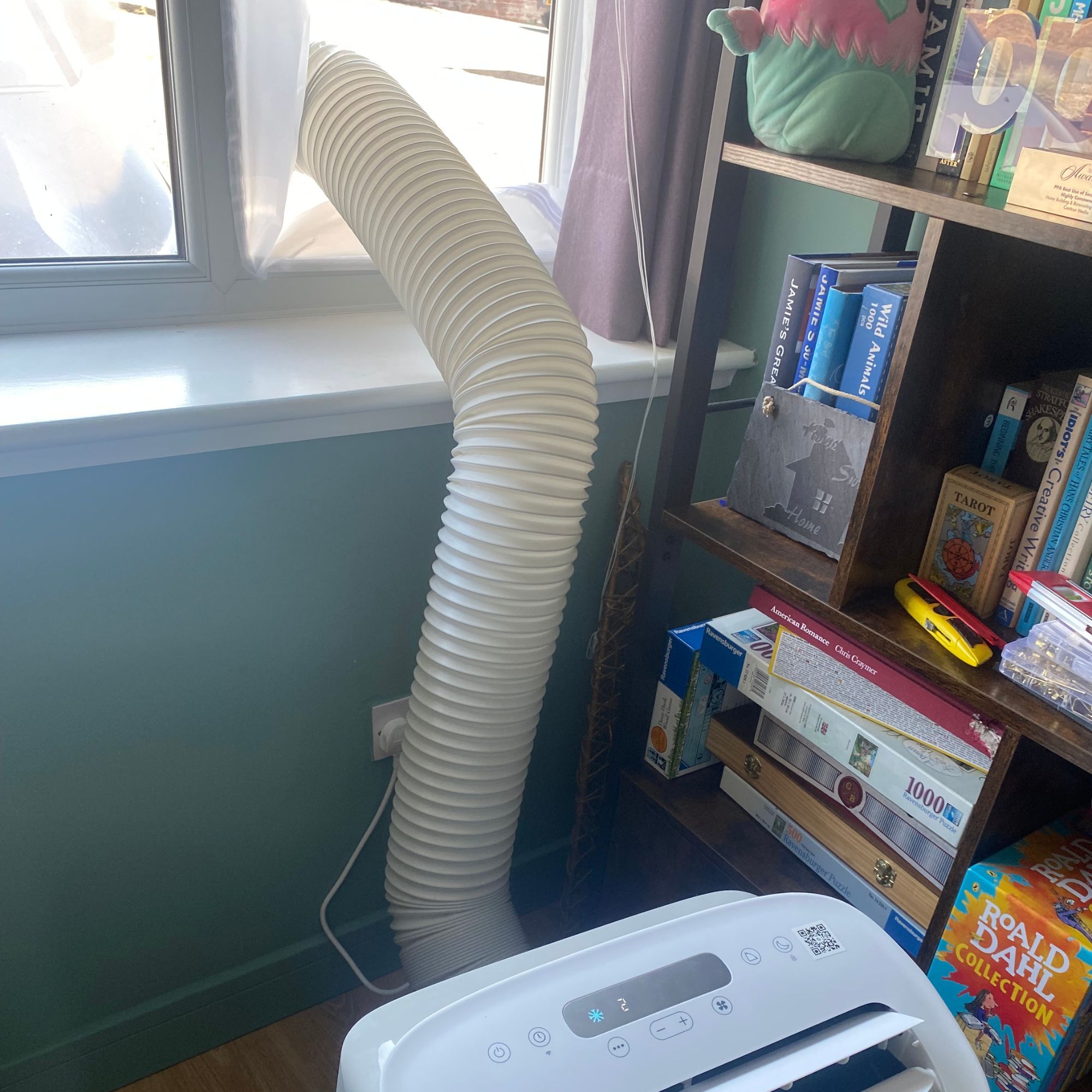 Meaco Cirro portable air conditioner vented out of a window in front of a bookcase in a home office