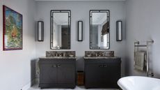 Bathroom with dark gray cabinets and Art Deco-style black framed mirrors