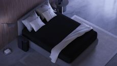 The Eight Sleep Pod 4 smart cooling mattress cover on a mattress in a bedroom, the Pod 4 control Hub to the side of the bed