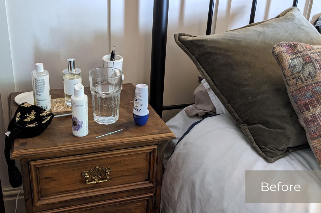 Before photo of my husband's ornate wooden bedside table with two drawers. There are bottles and lotions and perfumes, deodorant and water as well as other items on the top.
