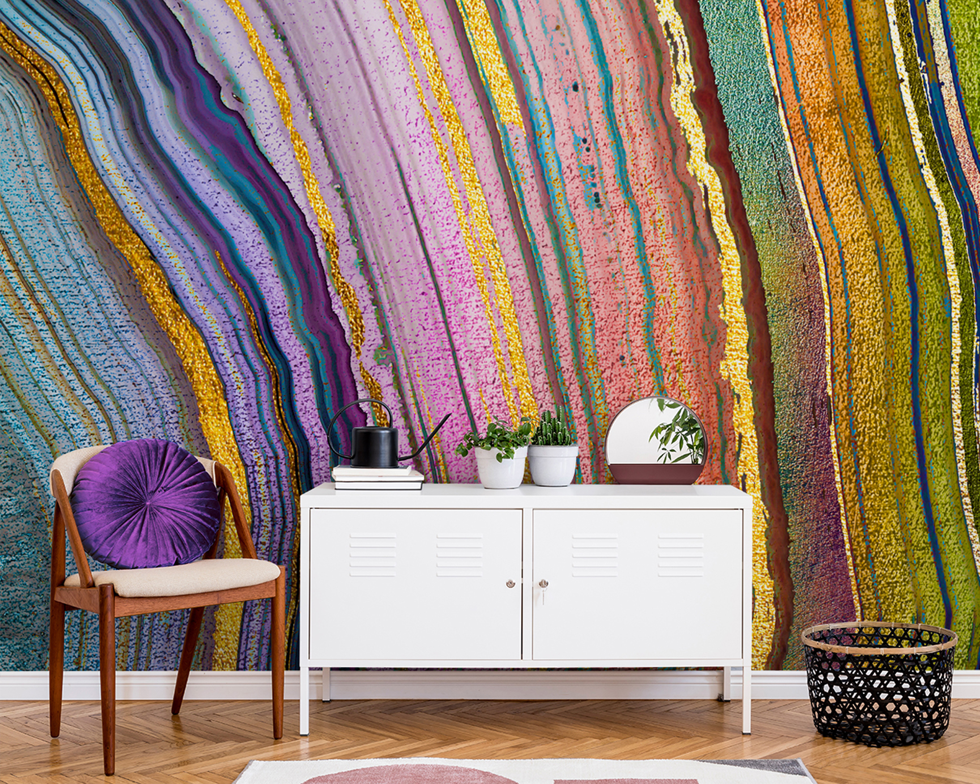 Rainbow agate design statement wall mural behind white, locker style low sideboard, woven basket, and chair with round purple cushion.