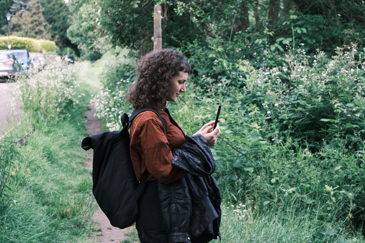 A woman with curly hair looking at a smartphone, taken on a Fujifilm X-T50