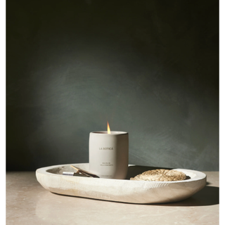 pale wooden oval bowl with scented candles and other decor bits on top