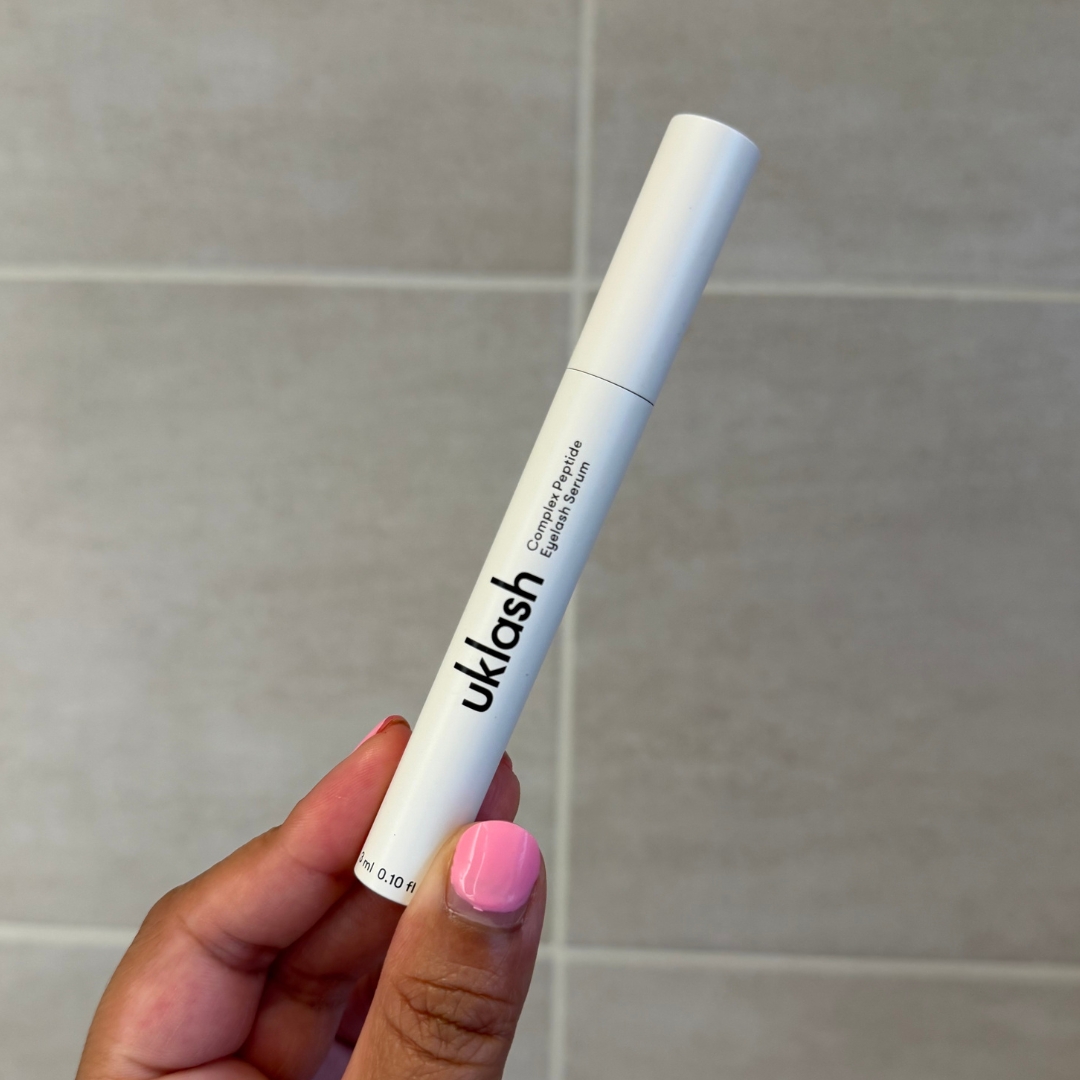 Hand holding empty tube of UKLASH Complex Peptide Lash Growth Serum