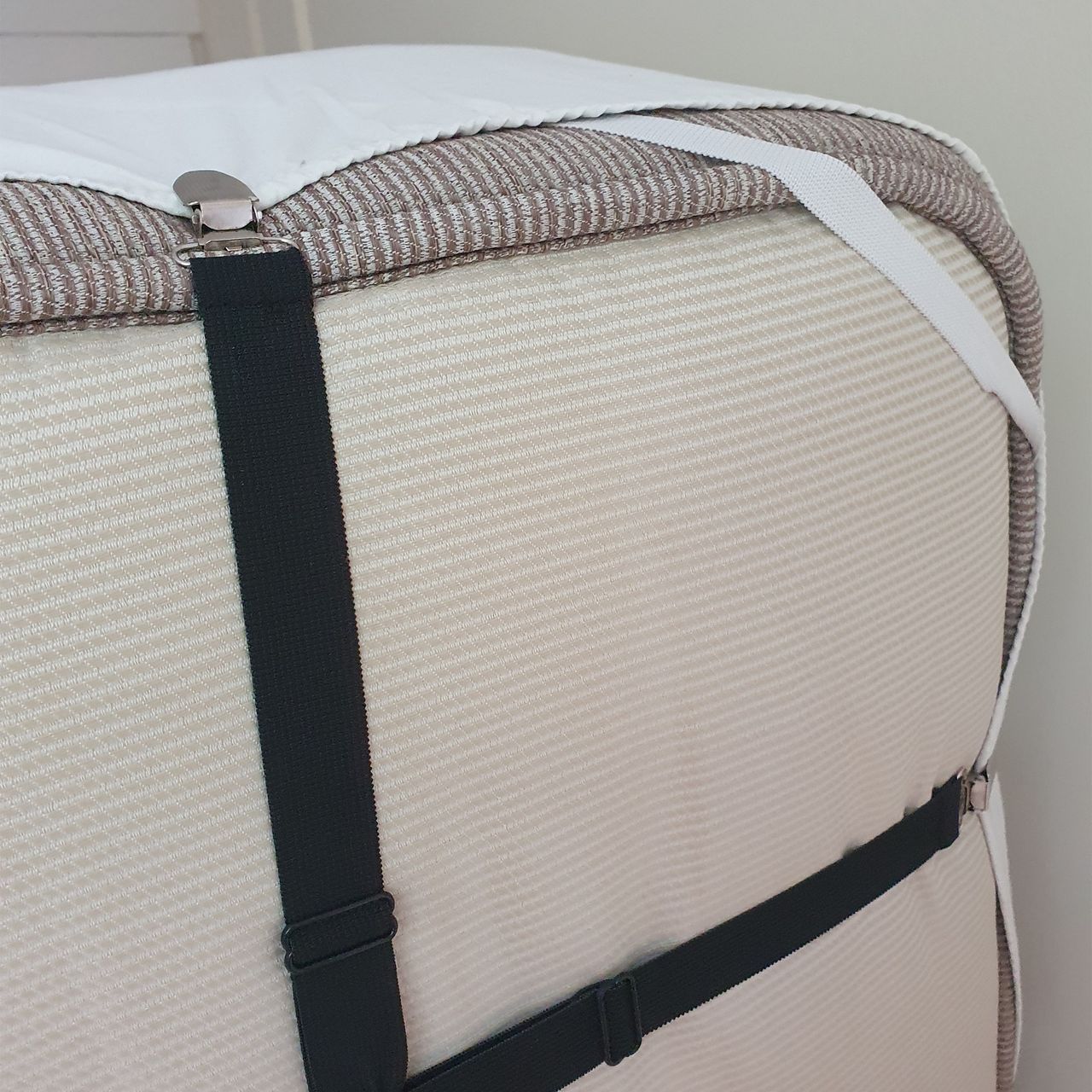 Black elasticated sheet straps being fitted to a white fitted sheet