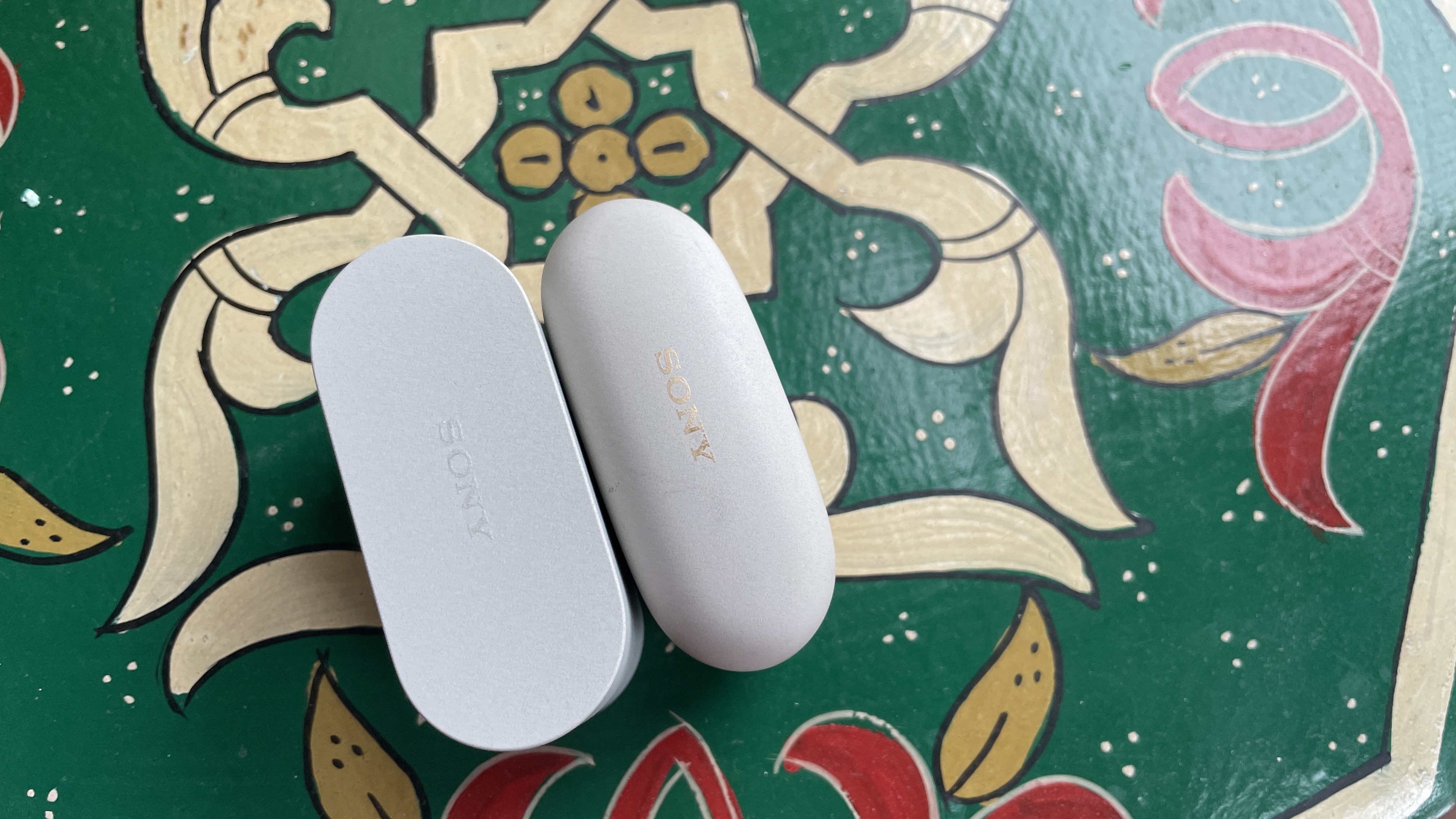 The Sony WF-10000XM6 next to the Sony WF-1000XM5, held in a hand, to show the size difference 