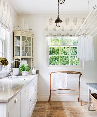 How to organize a laundry room, with a pulley drying rack, wooden clothes rail and stone countertop in a neutral and white scheme.