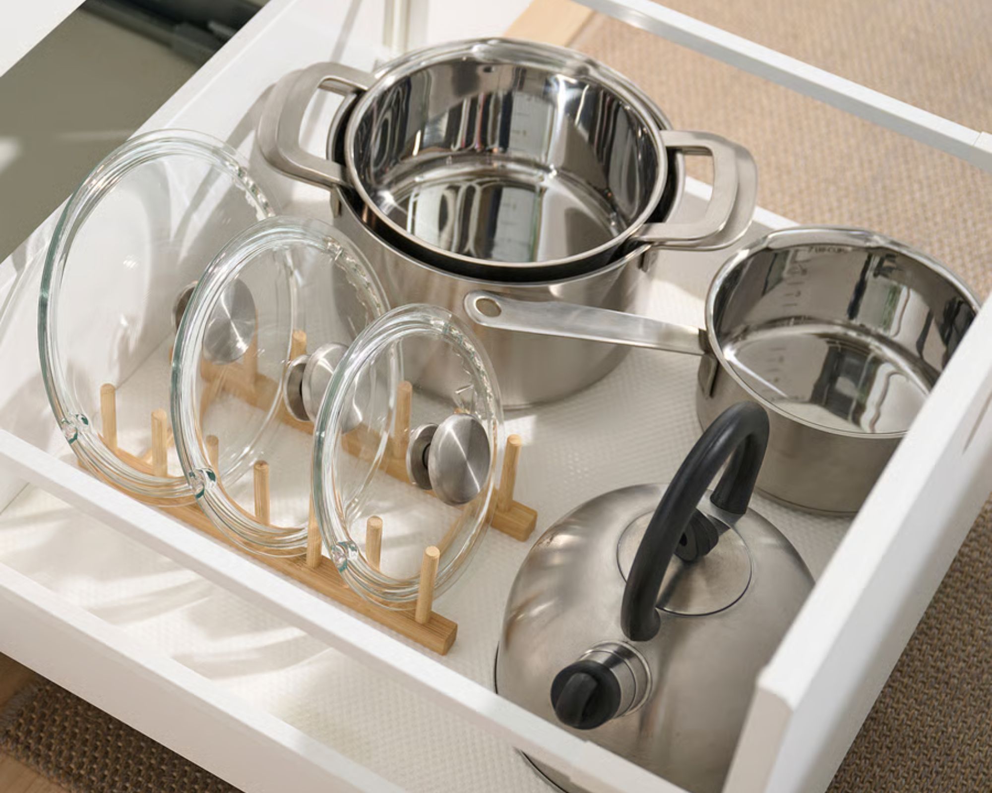 IKEA OSTBIT bamboo kitchen organiser in use in a lower drawer, and it's holding three glass pan lids