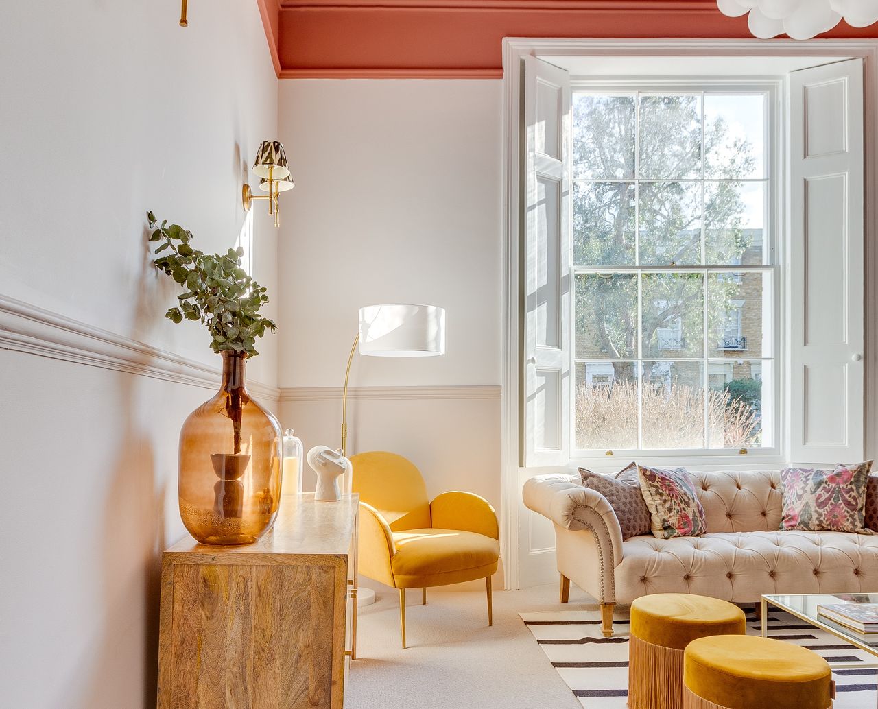 A living room with white walls, beige wainscoting, and a terracotta ceiling