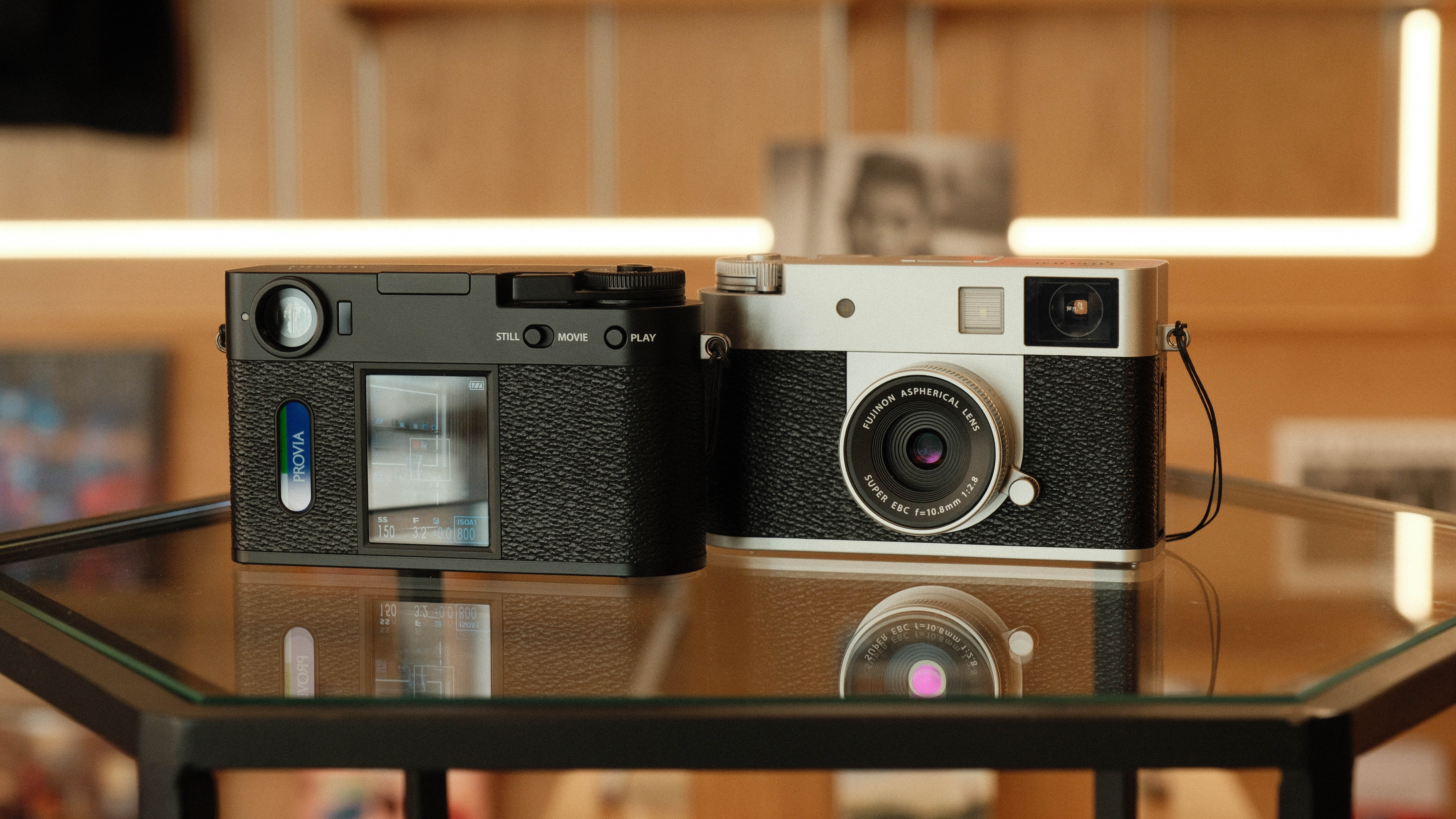 Two Fujifilm X Half cameras next to each other showing the front and rear of the camera
