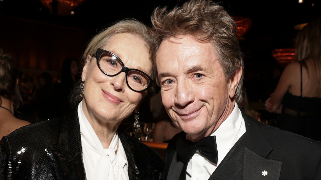 Meryl Streep wears a white pussy bow blouse and a black sequin jacket while she poses with Martin Short, who is wearing a tuxedo