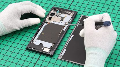 A Samsung Galaxy phone being repaired on a green mat