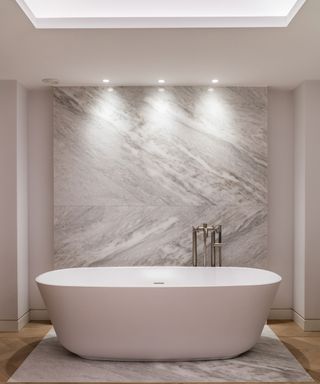An example of LED bathroom lighting ideas showing a large white bath below three spotlights