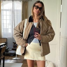 Anne-Laure Mais wearing a barn jacket, cardigan, mini slip skirt, and burgundy ballet flats.