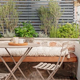 terrace area with small table and chairs, bench seating and planters on wall
