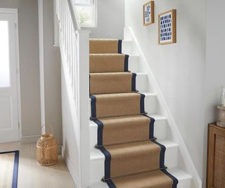 white painted stairs with jute navy bordered stair runner and stair rods