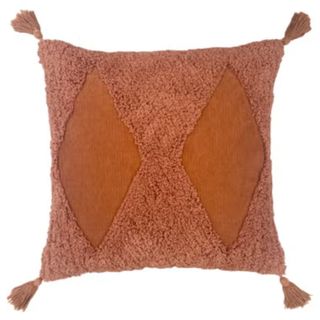 A burnt orange cushion with tassels