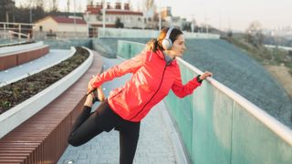 Woman stretching during workout while wearing headphones and sports watch