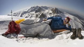Best sleeping pad: a man resting in a sleeping bag on a snowy mountain