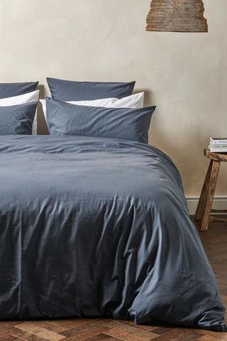 Bedfolk ink blue bedding on bed with white pillows and bedside table