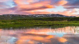Summer Solstice 2023: Lenticular clouds reflected in a lake, Iceland - stock photo