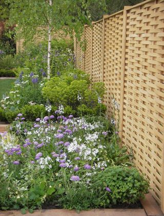 A woven oak fence with flower beds in a large backyard
