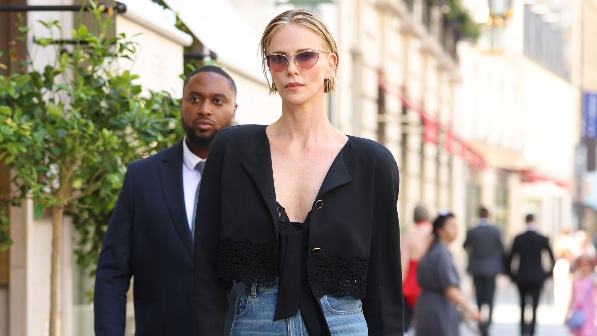 Charlize Theron wears wide-leg jeans with tall clog heels and a black shirt.