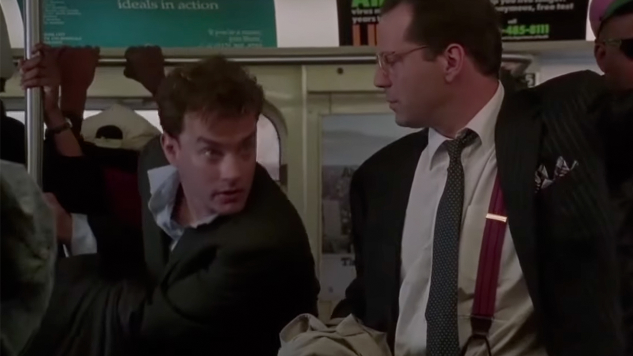 Tom Hanks looking worried with Bruce Willis on a subway car in The Bonfire of the Vanities.