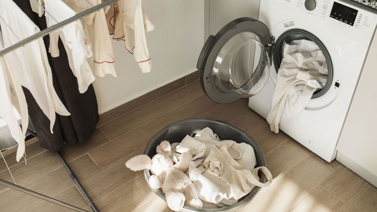 tumble dryer with open door and washing on the floor