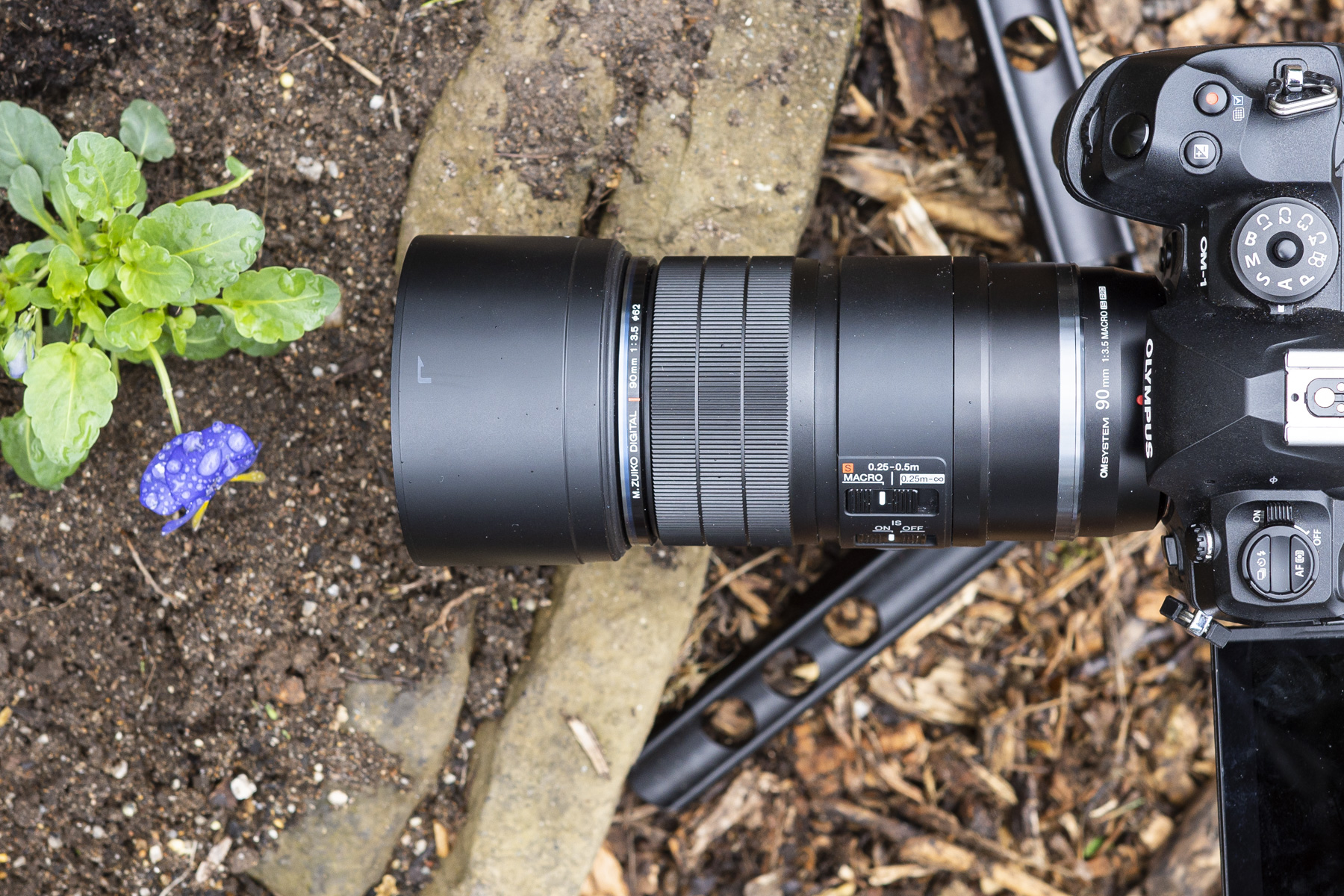 OM System 90mm macro lens on the ground from above attached to the OM-1 camera