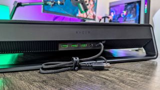 The Razer Laptop Cooling Pad on the desk, seen from behind to reveal the three USB Type-A 2.0 ports, 36W DC power port, and connecting cable.