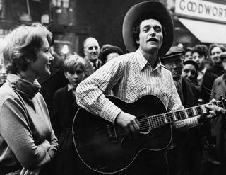 Ramblin' Jack Elliott, with his wife June (left), playing the guitar at an event in Stratford, London, circa 1960