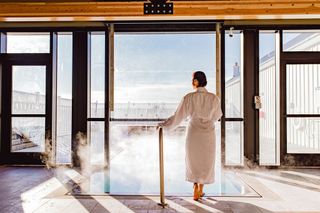 A woman stands in front of the indoor/outdoor lounge pool at Miraval Berkshires' spa