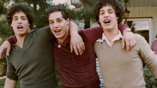 A still from the Three Identical Strangers documentary of three teenage men laughing and hugging.