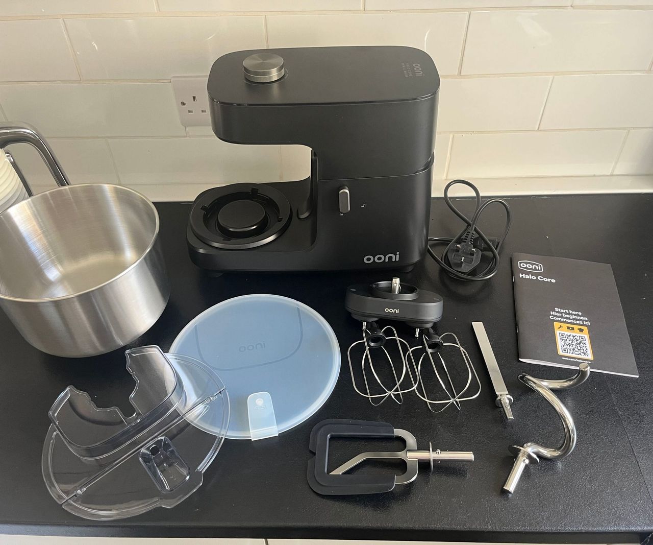 The Ooni Halo Core Spiral Mixer on a back kitchen counter surrounded by its accessories.
