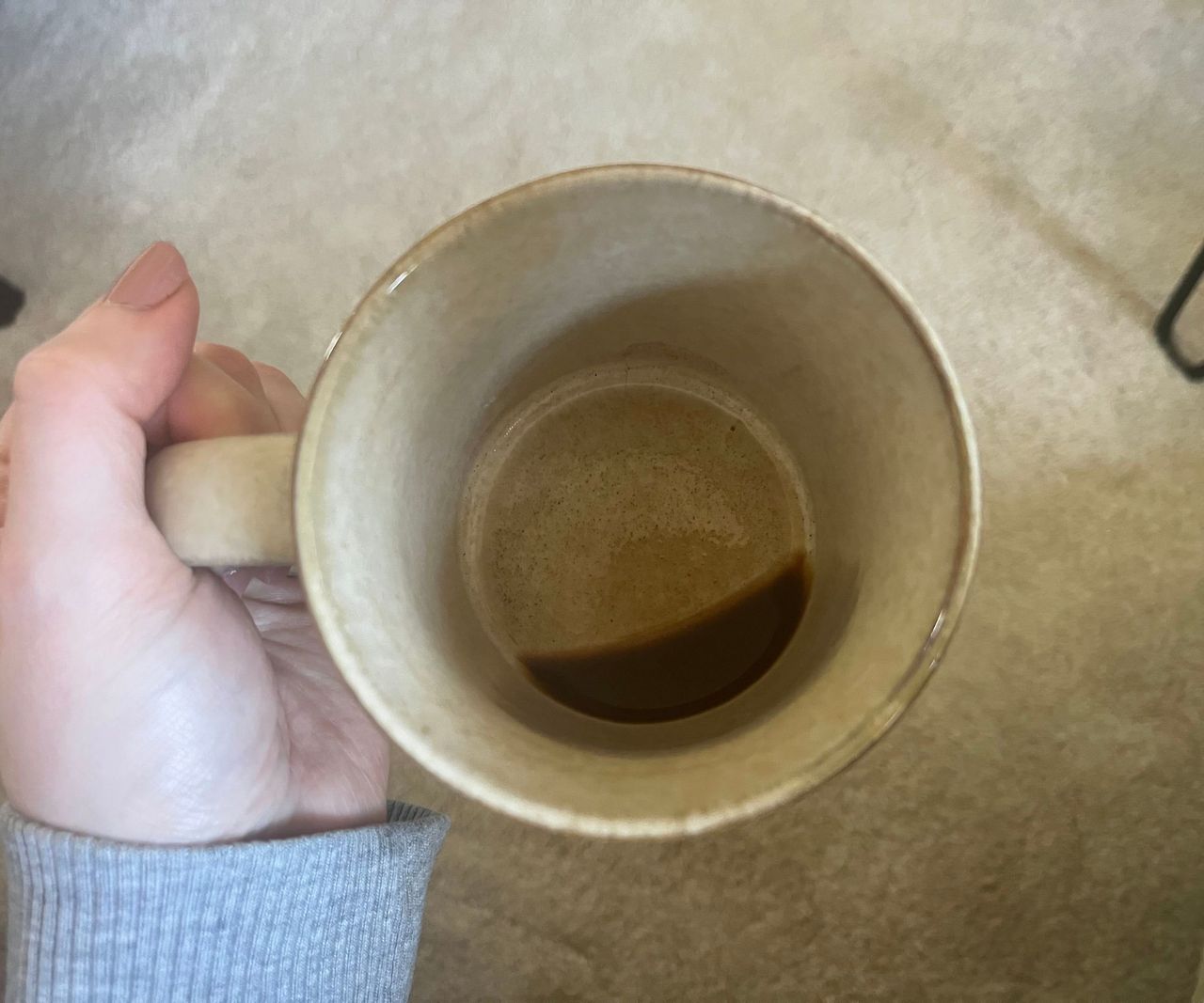 The bottom of a coffee mug with a small amount of coffee in the base.