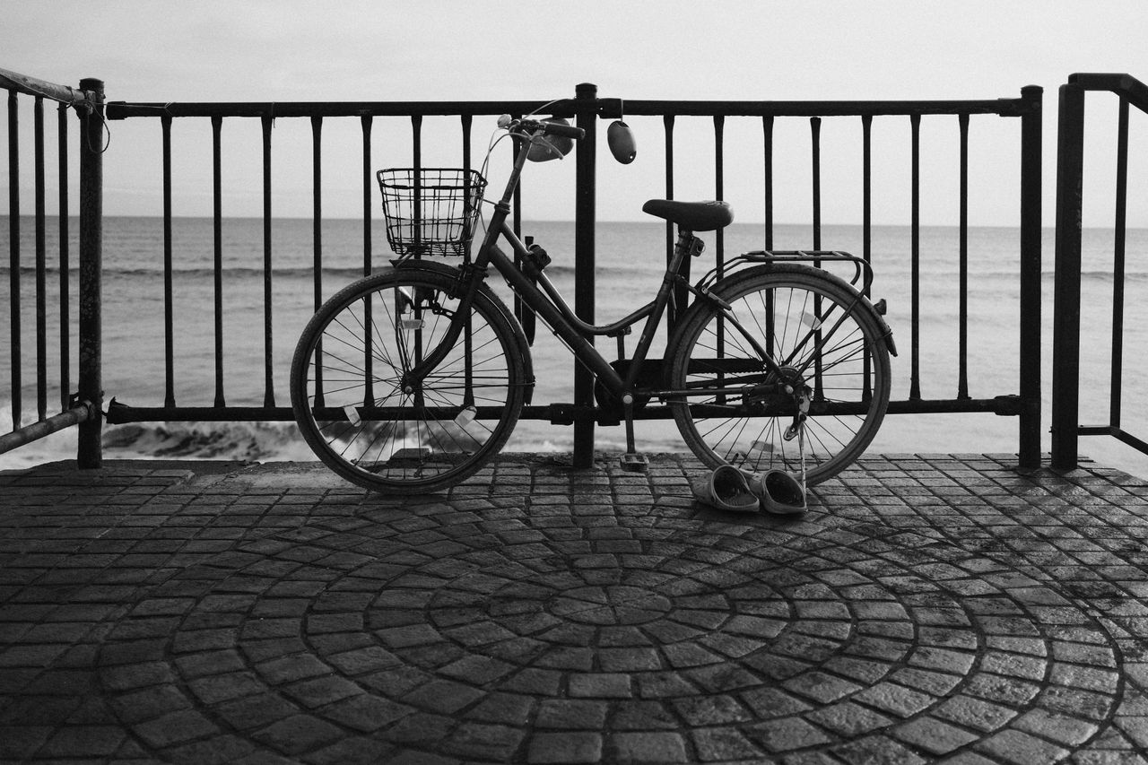 Bike parked up against a railing next to some shoes in black and white